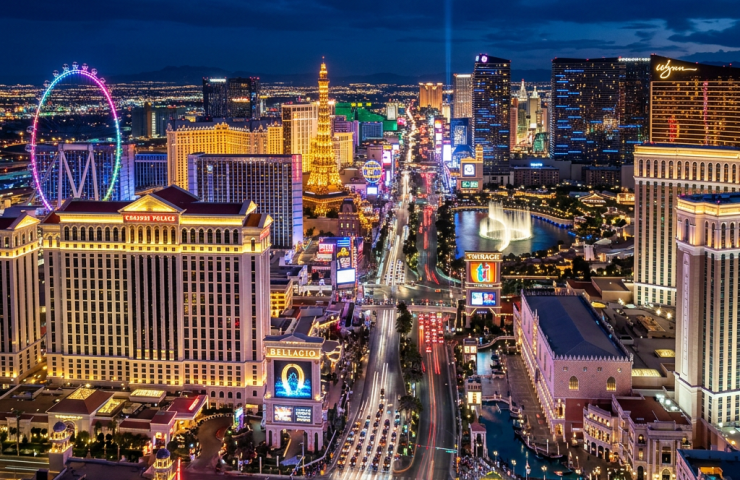 Aerial view of the Las Vegas Strip at night with bright city lights, hotels, and a large ferris wheel